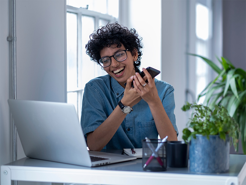 Young smiling woman at work looking at laptop