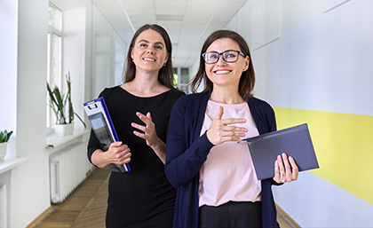 Two women holding notepads walking in the office