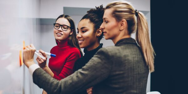 women writing on a whiteboard at work